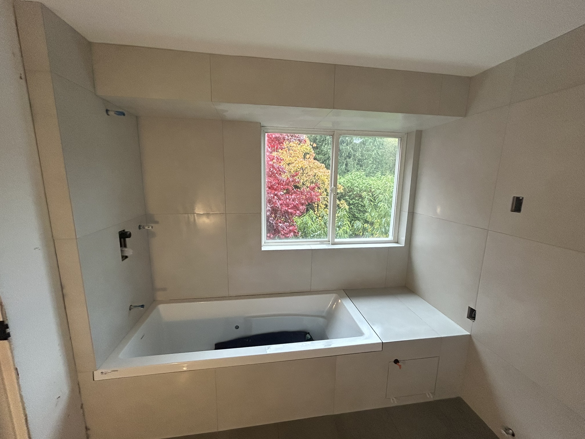Beige tiled bathroom with garden view