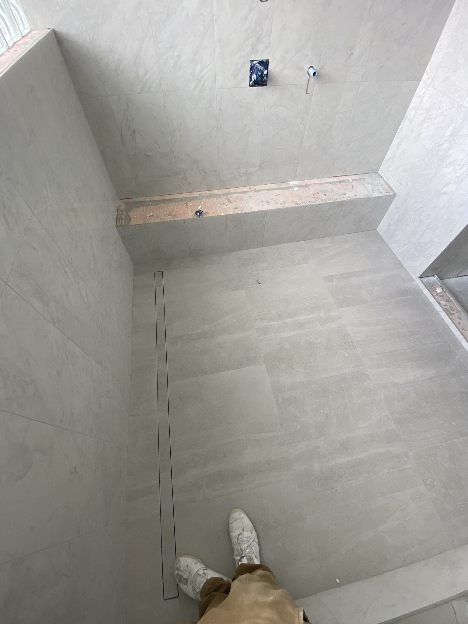 Grey stone shower with linear drain and bench