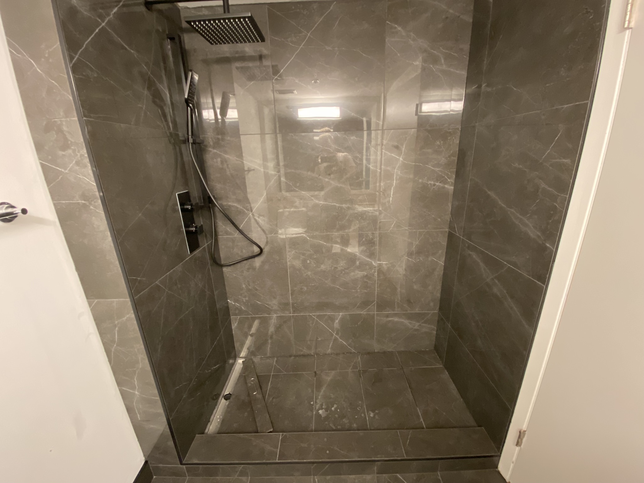 Dark marble shower with rain head and glass