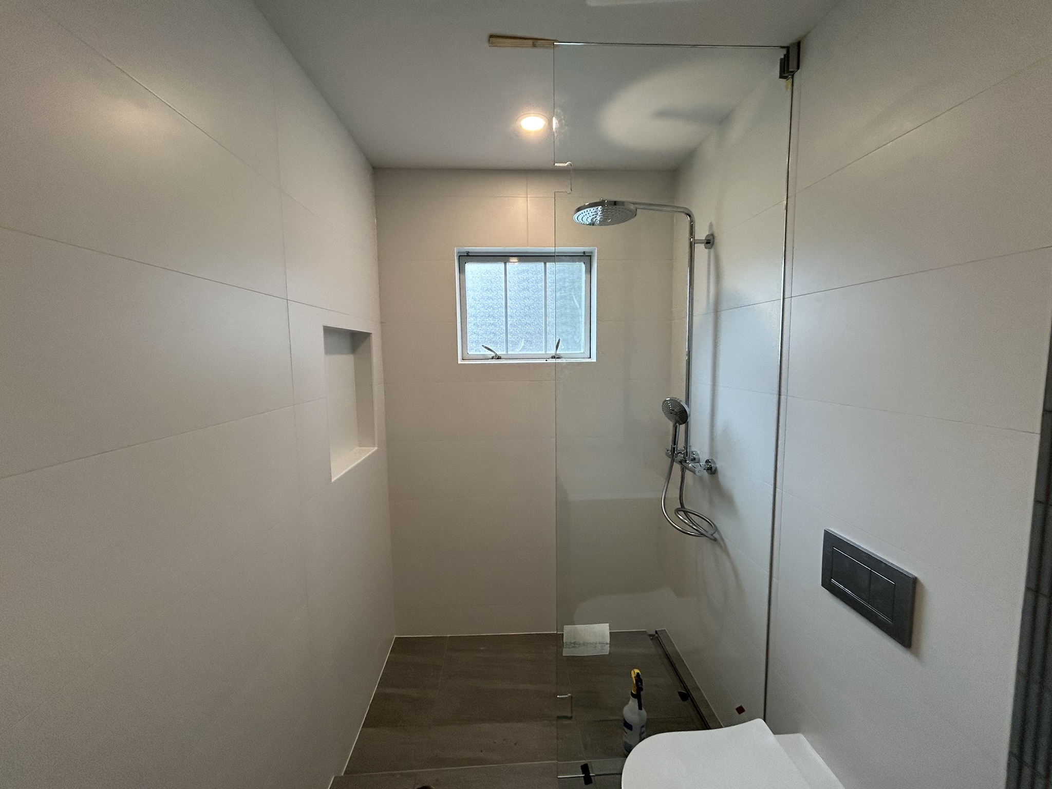 White tile shower with glass door and niche