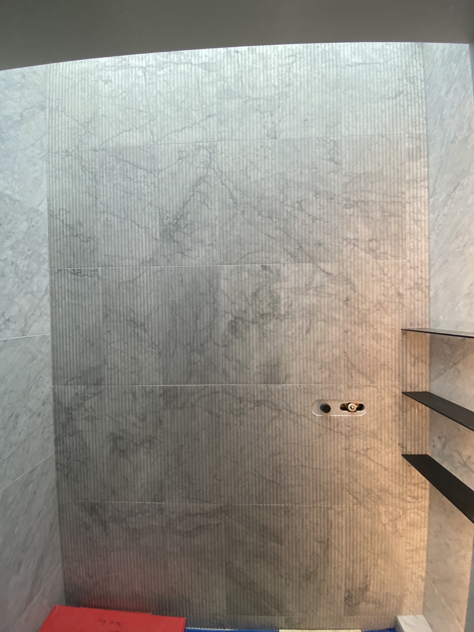 Curved marble shower with floating shelves