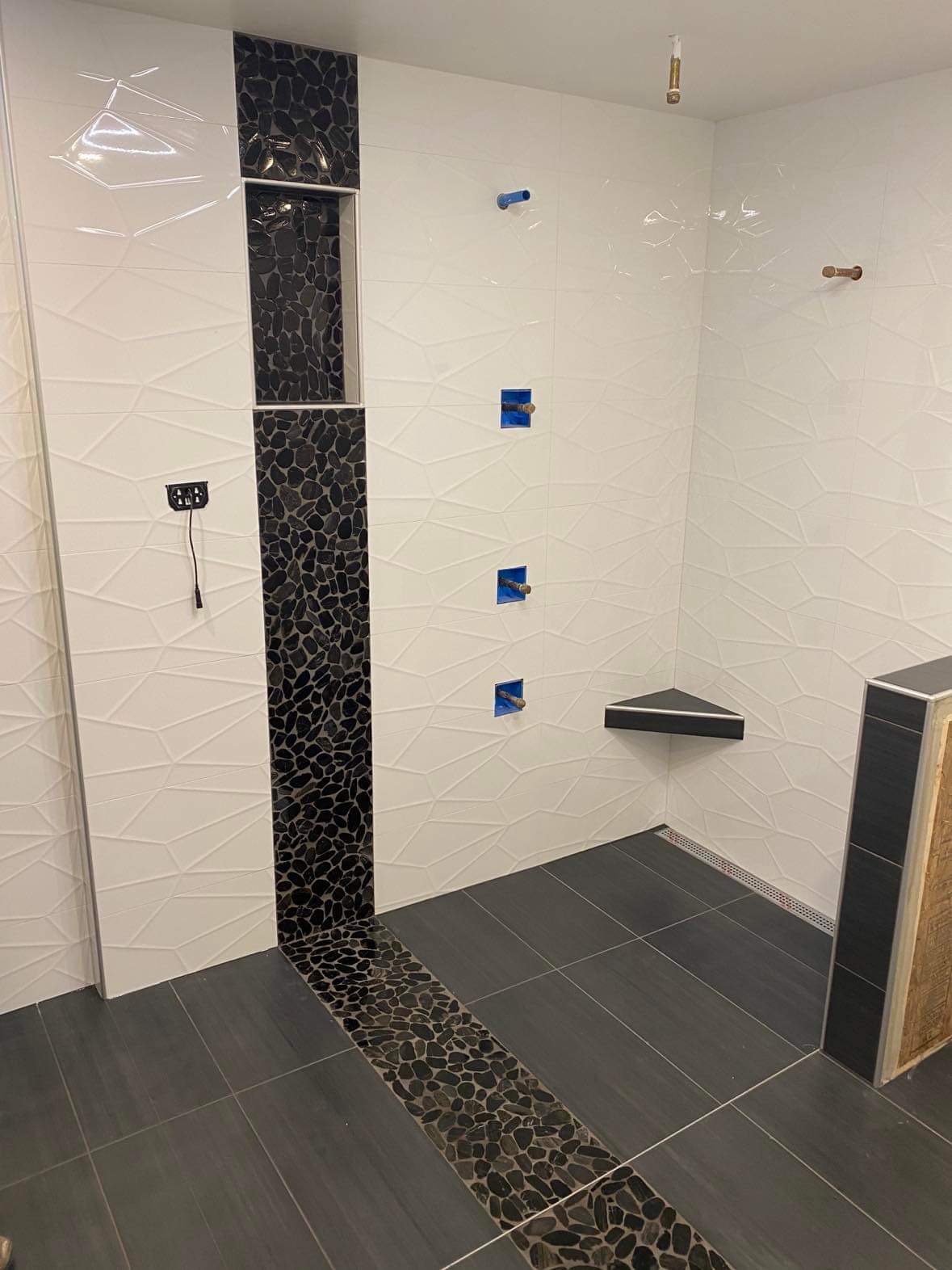 3D white tile shower with black pebble accent