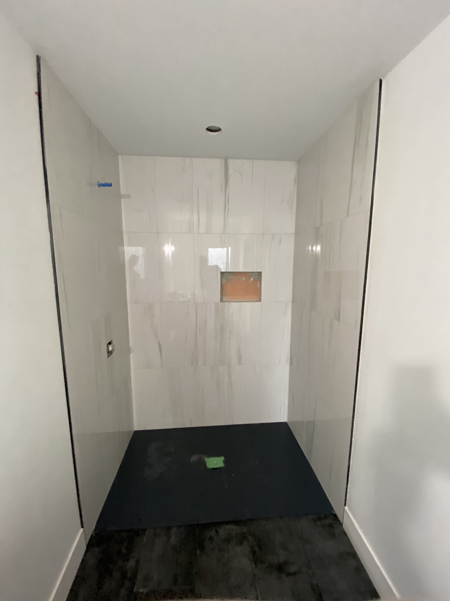 White marble shower with black floor niche