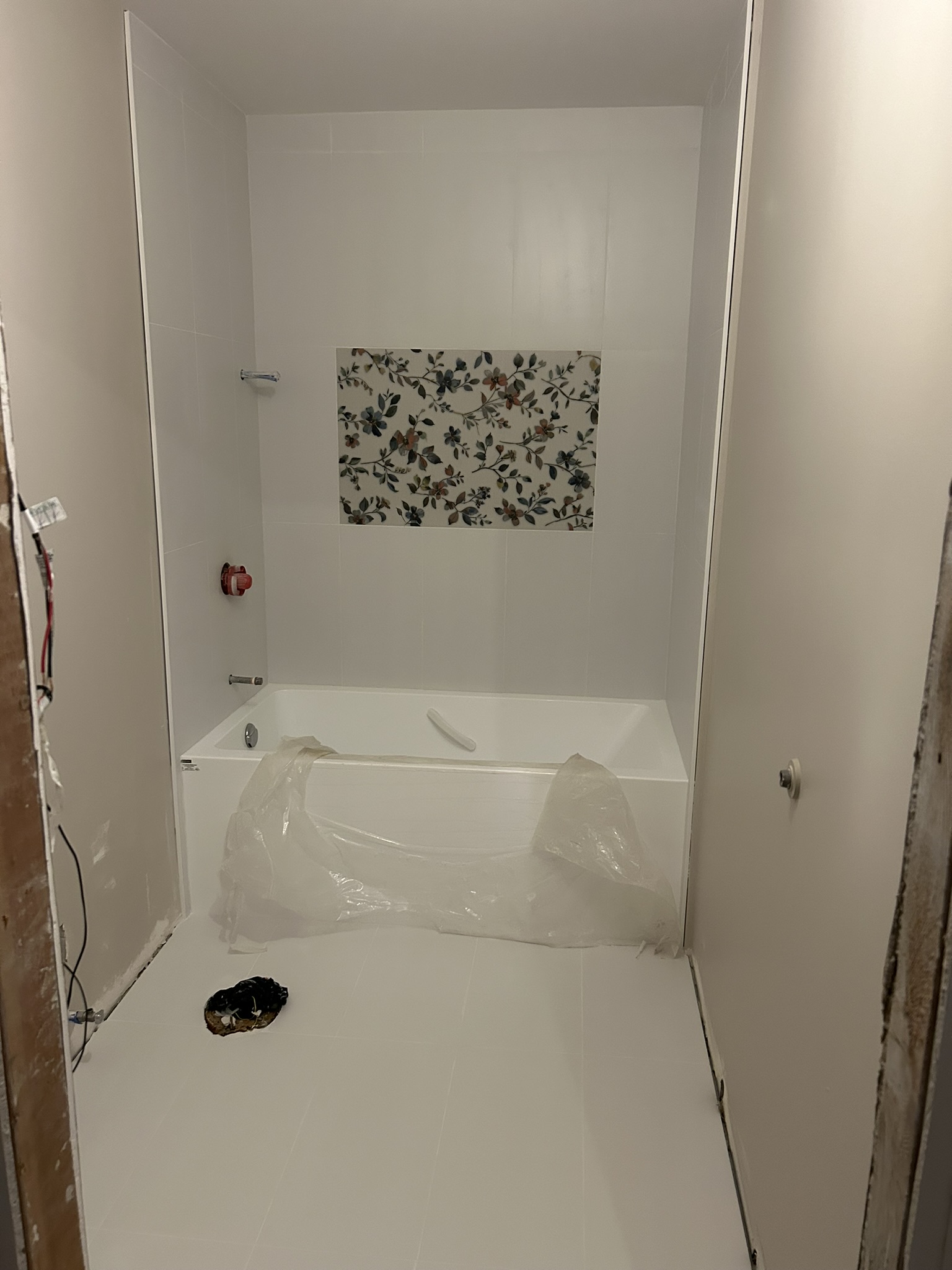 White tile tub surround with floral mosaic niche