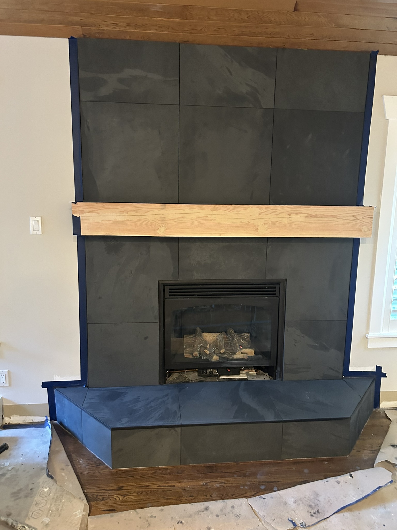 Black slate tile fireplace surround with wood mantel