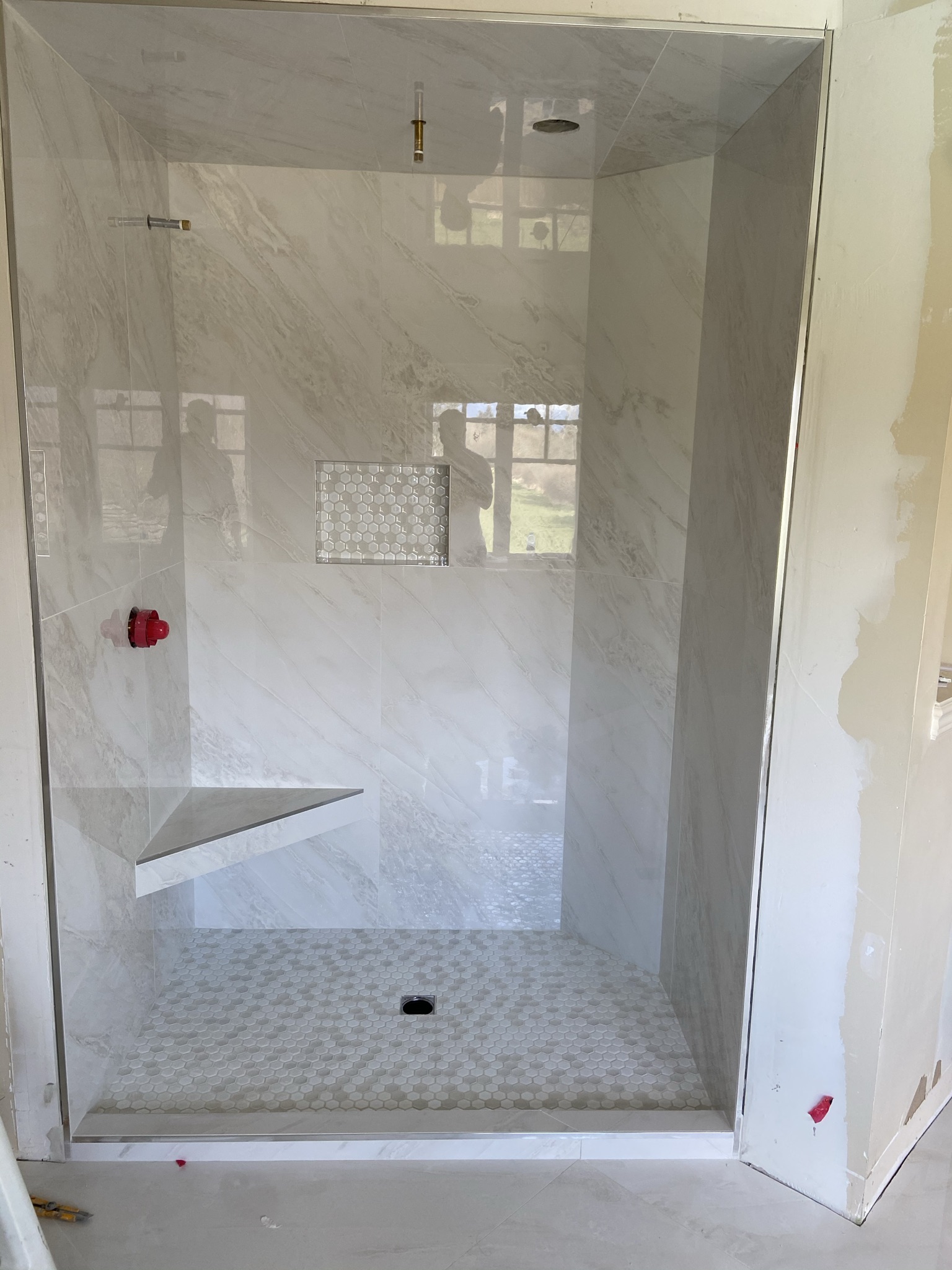 White marble shower with hex niche and bench