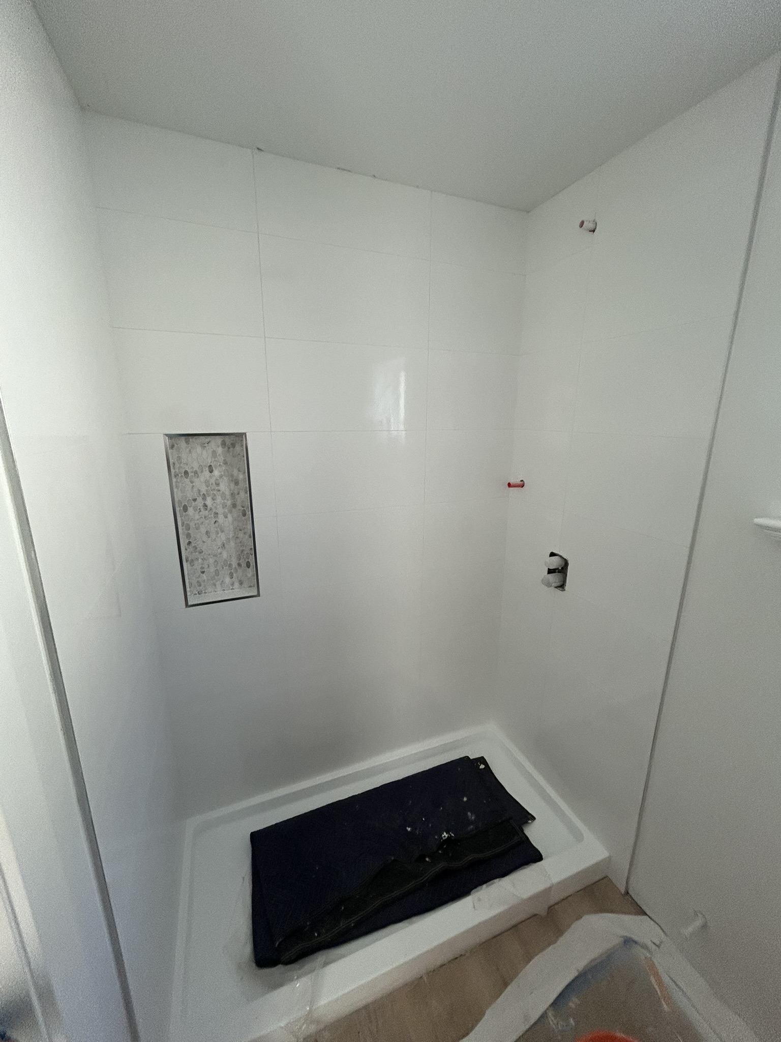 White tile shower with hex mosaic niche